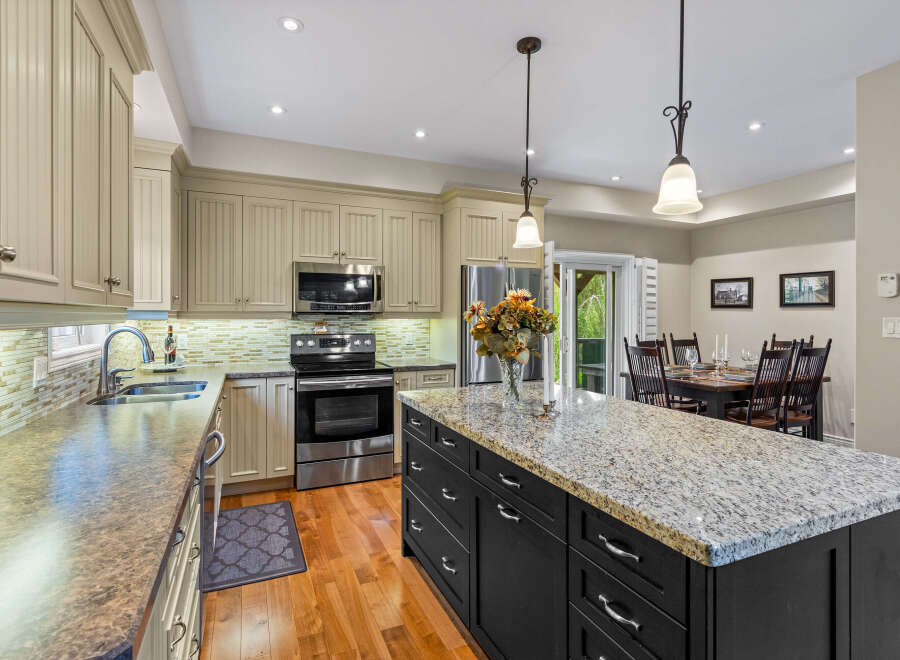 This spacious kitchen boasts custom cabinetry, a large granite island, and stainless steel appliances, perfect for any home chef.