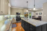 This spacious kitchen boasts custom cabinetry, a large granite island, and stainless steel appliances, perfect for any home chef.