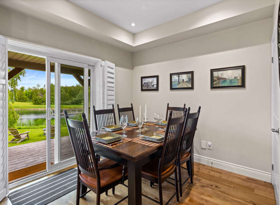 Enjoy elegant dining with a view in this beautifully set dining room, featuring a dark wood table and chairs ready for guests.