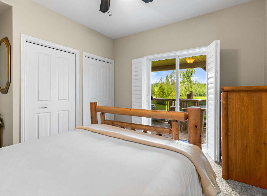 This cozy bedroom features a rustic log bed and a convenient access to the outdoors through a sliding glass door.
