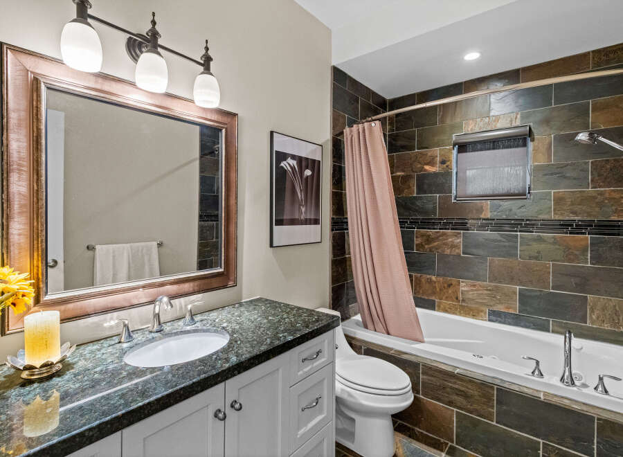 This elegant bathroom features a spacious vanity with a granite countertop and a large, ornate mirror.