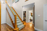 Step into this inviting entryway featuring a grand wooden staircase with plush carpeting and elegant white balusters.