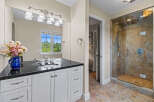 This elegant bathroom features a spacious vanity with a granite countertop and ample storage, complemented by a large mirror and decorative lighting.