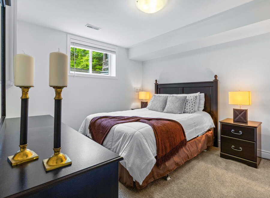 This cozy bedroom features a comfortable queen-size bed adorned with a warm rust-colored throw blanket and plush pillows.