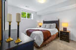 This cozy bedroom features a comfortable queen-size bed adorned with a warm rust-colored throw blanket and plush pillows.