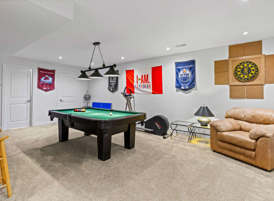This basement recreation room is perfect for entertaining and unwinding, featuring a full-size pool table ready for a game.