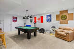 This basement recreation room is perfect for entertaining and unwinding, featuring a full-size pool table ready for a game.