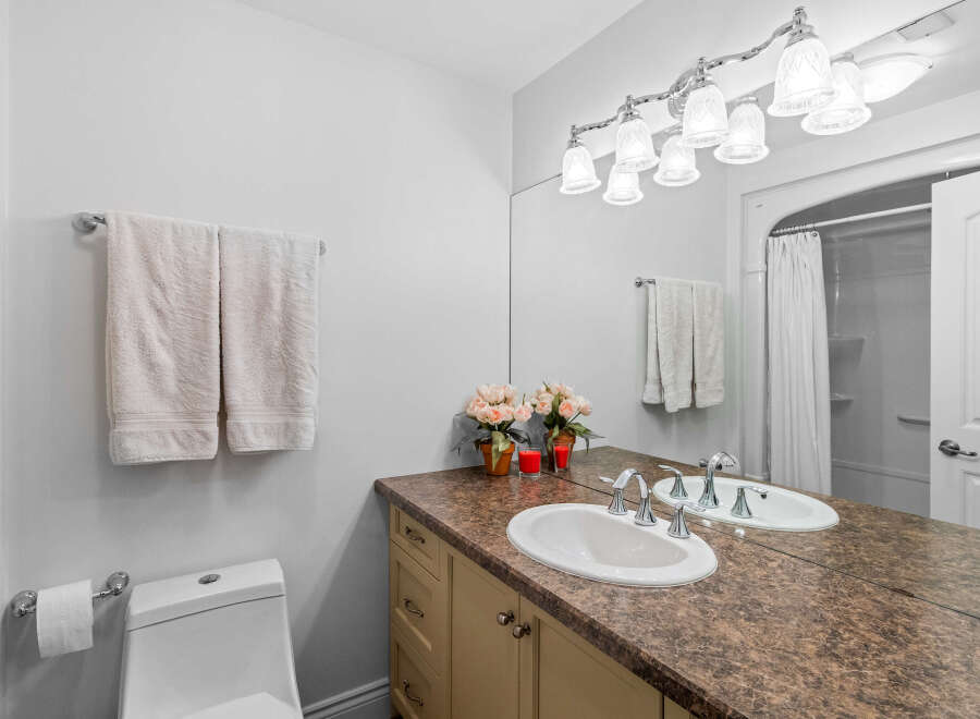 This bright and clean bathroom features a spacious vanity with a double sink and ample counter space, perfect for morning routines.