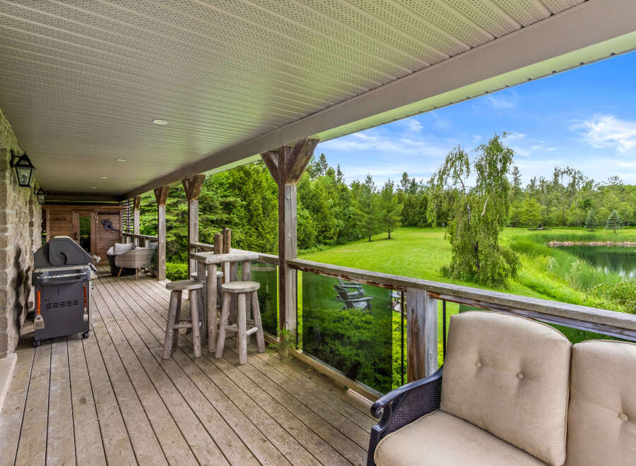 Enjoy outdoor living on this spacious covered deck, complete with a grill for entertaining and a charming bar area with stools.