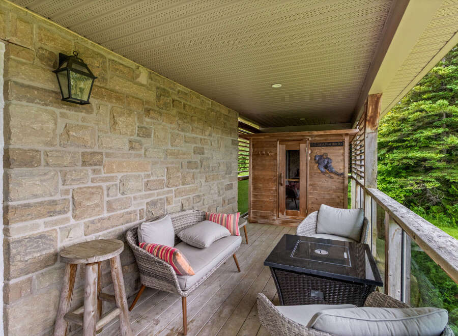 Enjoy outdoor living on this charming covered porch, featuring a cozy seating area with plush cushions and a stylish fire pit table perfect for evening gatherings.