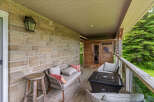 Enjoy outdoor living on this charming covered porch, featuring a cozy seating area with plush cushions and a stylish fire pit table perfect for evening gatherings.
