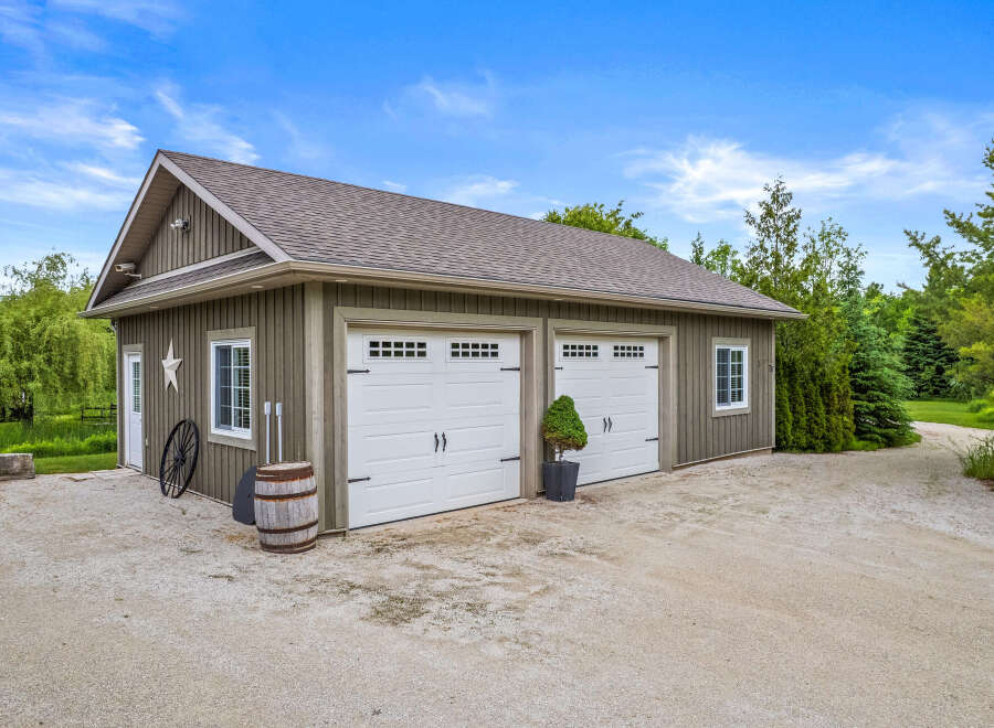 Discover this charming property featuring a spacious garage with two white doors, perfect for vehicle storage or a workshop.