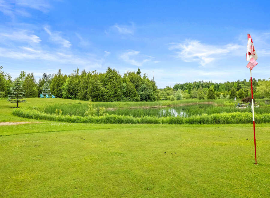 Enjoy the serene beauty of this property, featuring a picturesque pond surrounded by lush greenery and mature trees.