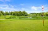 Enjoy the serene beauty of this property, featuring a picturesque pond surrounded by lush greenery and mature trees.