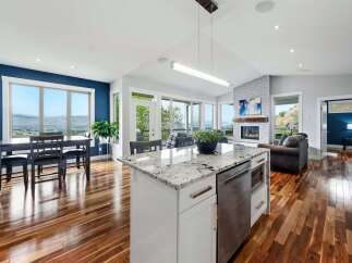 Experience breathtaking panoramic views from this stunning open-concept living space, featuring a modern kitchen island with granite countertops and a cozy living area centered around a beautiful fireplace.