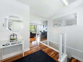 Step into this bright and airy entryway, featuring a sleek console table with a decorative mirror above.