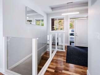 Step into a bright and modern entryway featuring a sleek glass railing system that enhances the sense of space.