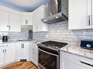 Experience modern kitchen luxury with sleek white cabinetry, granite countertops, and a striking subway tile backsplash.