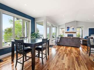 Experience breathtaking views from this stunning dining area, featuring a dark wood table and chairs complemented by a vibrant blue accent wall.
