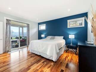 Experience luxurious living in this stunning bedroom featuring a king-sized bed with crisp white linens, complemented by a bold navy accent wall.