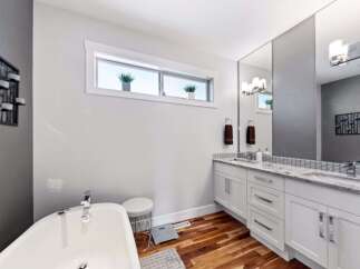 Experience luxury in this modern bathroom featuring a freestanding soaking tub and a spacious double vanity with granite countertops.