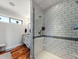 Experience modern luxury in this stunning bathroom featuring a spacious walk-in shower with sleek subway tile and a decorative mosaic accent band.