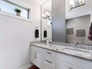 This modern bathroom features a sleek white vanity with a granite countertop and dual sinks, perfect for busy mornings.