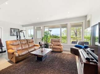 Experience ultimate comfort and entertainment in this spacious living area, featuring a plush leather sofa and recliner perfect for relaxation.