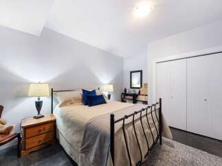 This charming bedroom features a cozy queen-size bed with plush bedding and two dark blue accent pillows.