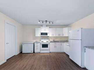 This kitchen features a full suite of white appliances, including a refrigerator, stove, and microwave, all set against clean white cabinetry.