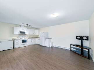 Discover this bright and airy studio apartment featuring a modern white kitchen equipped with essential appliances and ample cabinet space.