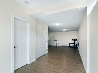 Discover modern living in this spacious apartment featuring a well-equipped kitchen with a refrigerator and ample cabinet space.
