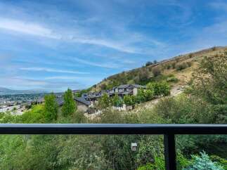 Experience breathtaking panoramic views from this stunning property, nestled on a hillside overlooking a vibrant community and distant mountains.