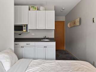 Discover this charming studio apartment featuring a compact kitchenette with a microwave and ample cabinet space, perfect for preparing simple meals.