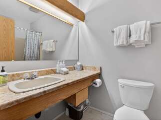 This bathroom features a spacious vanity with a marble-patterned countertop, offering ample space for toiletries and personal care items.
