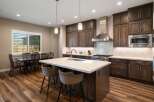 Experience modern luxury in this stunning kitchen, featuring rich dark wood cabinetry, a sleek stainless steel range hood, and a spacious quartz island perfect for entertaining.