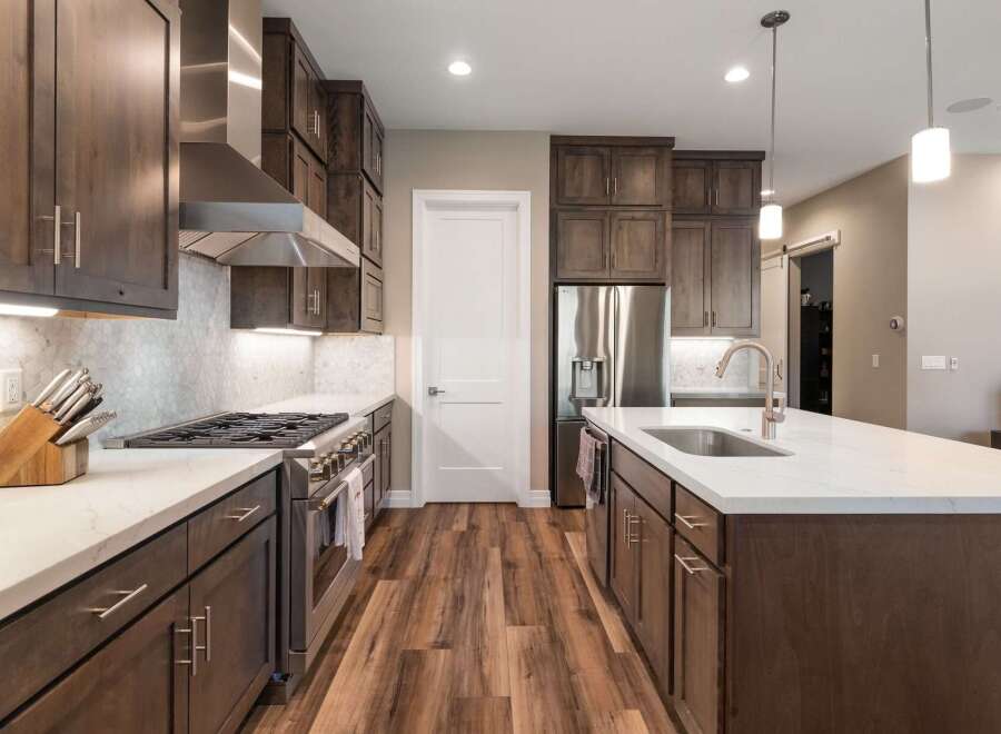 Experience luxury in this stunning modern kitchen, featuring sleek dark wood cabinetry and gleaming stainless steel appliances.