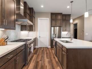 Experience luxury in this stunning modern kitchen, featuring sleek dark wood cabinetry and gleaming stainless steel appliances.