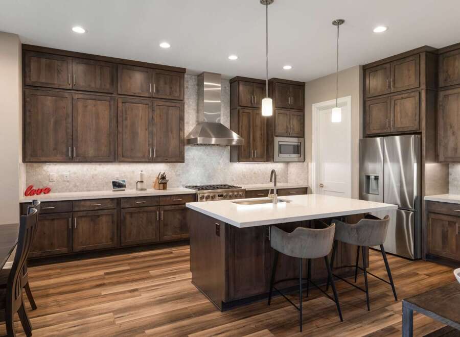 Experience luxury in this stunning modern kitchen, featuring rich dark wood cabinetry and a sleek stainless steel range hood.