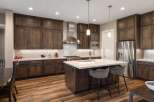Experience luxury in this stunning modern kitchen, featuring rich dark wood cabinetry and a sleek stainless steel range hood.