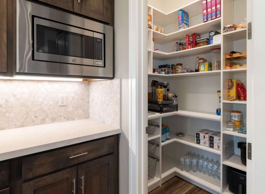 Discover ample storage with this spacious walk-in pantry, featuring custom shelving to organize all your culinary essentials.