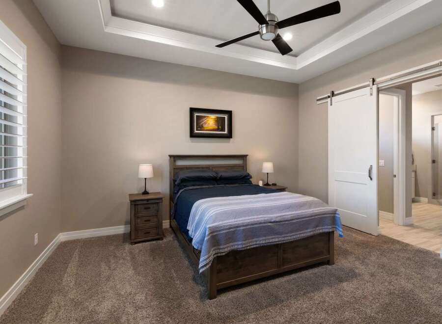 Experience luxurious comfort in this master bedroom, featuring a spacious king-size bed with elegant dark wood furniture and a cozy striped throw.