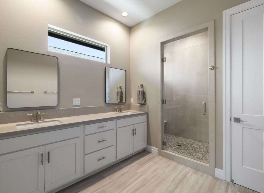 This modern bathroom features a spacious double vanity with sleek countertops and ample storage.
