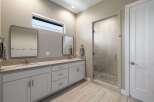 This modern bathroom features a spacious double vanity with sleek countertops and ample storage.