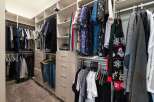 Discover ample storage in this spacious walk-in closet, featuring custom shelving and multiple drawers to keep your wardrobe organized.