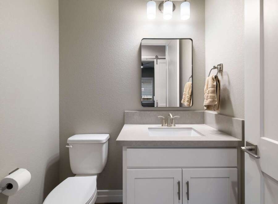 This modern bathroom features a sleek vanity with a quartz countertop and undermount sink, complemented by a brushed nickel faucet.