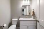 This modern bathroom features a sleek vanity with a quartz countertop and undermount sink, complemented by a brushed nickel faucet.