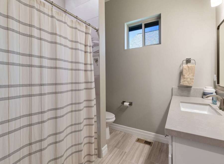 This modern bathroom features a sleek vanity with a stone countertop and a clean white sink, complemented by a brushed nickel faucet.