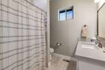 This modern bathroom features a sleek vanity with a stone countertop and a clean white sink, complemented by a brushed nickel faucet.