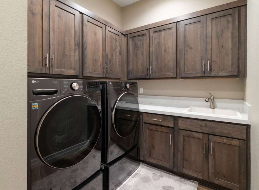 This laundry room boasts ample storage with dark wood cabinetry, both above and below the countertop.